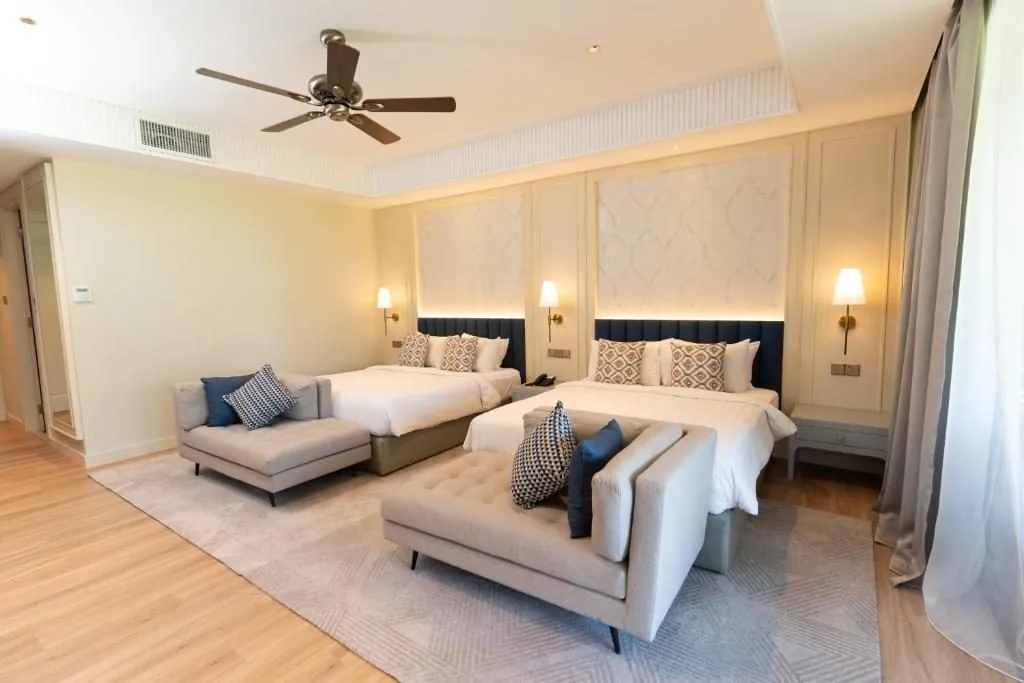 Hotel room with grey chaise lounges and twin beds