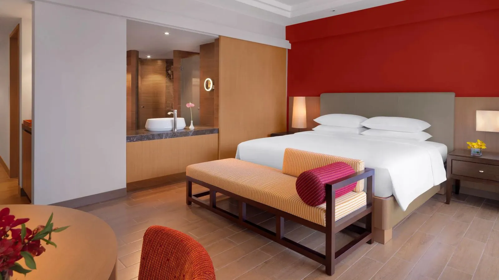 Hotel bedroom with red accent wall and ensuite vanity