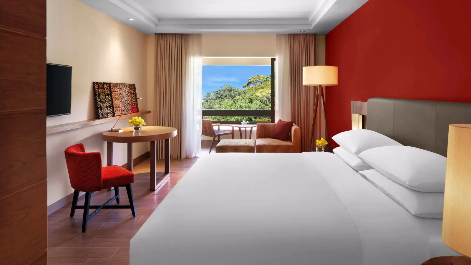 Hotel bedroom with red accent wall and balcony seating