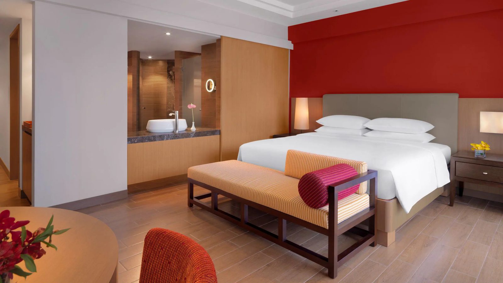 Hotel bedroom with red accent wall and ensuite vanity