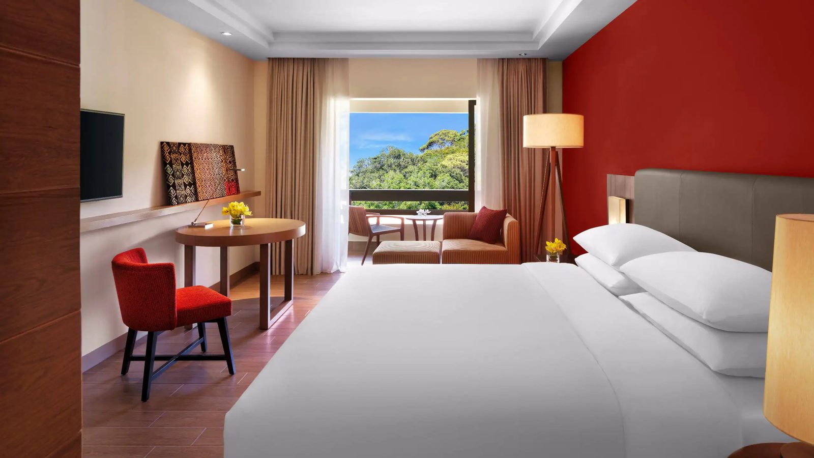 Hotel bedroom with red accent wall and balcony seating